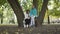 Nice brunette caucasian woman reading the book to a young blond girl in the sunny park. Two people in casual clothing