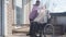 Nice Caucasian woman in eyeglasses bringing blanket for disabled elderly man sitting in wheelchair outdoors. Nurse