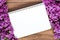 Nice composition of a blank notebook and lilac flowers on the brown wooden surface