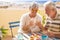 Nice couple of retired adult stay together on the roofto pterrace eating and drinking some food and drink. happy smile people