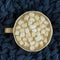 Nice Cup of coffee with marshmallow. Blue knitted background