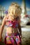 Nice dressed blond little girl on the beach in the summertime looking down