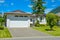 Nice family house with wide garage door on sunny day in British Columbia.