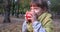 Nice female child smiles and bites apple on background of yellow foliage in autumn outside