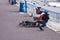 Nice, France, March 2019. On a warm sunny day, a man feeds the pigeons of the city with bread against the turquoise sea of ??the