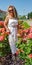 Nice girl in a white dress and curly hair among rose bushes