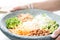 Nice image of a woman serving fresh salad in a buddha bowl.