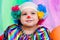 A nice kid wearing clown clothes and hair. The boy is very happy