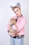 Nice kind woman with a short haircut and fur ears in sports clothes and jeans is holding her beloved pet on a white background in