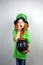 Nice littel girl with decorative red beard in green dress and leprechaun\\\'s hat, kissing golden coin with four-petal shamrock