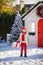 Nice little boy with red hat and green glasses finds a big present near the Christmas tree