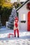 Nice little boy with red hat and green glasses and his big present near the Christmas tree