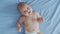 A nice little caucasian newborn baby is funny smiling, lying at the back. Portrait of a playful and energetic child