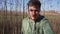 Nice-looking caucasian young guy is walking in country side alone along fields.