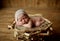 Nice newborn baby with a little linen cap on her head is sleeping in a basket