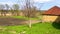 Nice old house with clay walls against the background of a meadow with grass, a garden