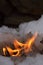 Nice picture of fire from stone of Calcium carbide burn with big flame in white snow. Piece of calcium acetylide reaction with