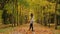 Nice pretty lady wandering in the park in autumn holding leaf bouquet turning around throwing leaves