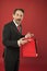 Nice purchase. Shocking discount. Mature businessman hold paper bag gift red background. Shopping concept. Christmas