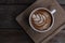 Nice shape of latte art coffee serve on wooden plate