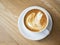 Nice shape of latte art coffee serve on wooden plate