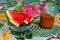 Nice shot of watermelon wedges and carrot juice, with tiny umbrellas on a colorful tablecloth