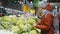 Nice Sporty Lady is Choosing Broccoli on a Stand with Vegetables in Supermarket