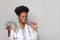 Nice successful african american woman doctor smiles and holds fan of money one hundred dollar against white background