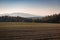 Nice sunset on hills with trees and field, colored photo, Czech