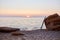 Nice sunset view on beach. Surfboard on rock and calm sea. Summer time, surfing sport and time to rest idea, copy space
