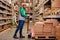 nice warehouse worker with manual pallet jack, working in storage room, transporting goods