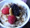 A nice warm bowl of oatmeal, topped with raspberries and blackberries with walnuts and drizzle of maple syrup