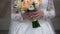 Nice wedding bouquet in bride`s hand. Clip. Fiancee in a beautiful white dress holding a beautiful bouquet of wedding