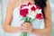 Nice wedding bouquet with red flowers in bride`s hands .