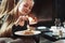 Nice white cream. Cute girl trying fresh cake while sits in the room with beautiful fireplace