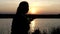 Nice woman sits on a lake bank drinking tea from a thermos