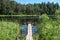 nice wooden plank boardwalk leans into blue lake with green shores and blue sky