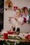A nice, young blonde girl alone in a white shirt and jeans in the  kitchen. The kitchen is decorated with New Year`s decor. New Ye