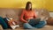 Nice young woman with dark short hair sitting on sofa, typing on laptop in room