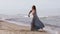 Nice young woman in a long dress dancing on the beach