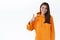 Nicely done. Pleased happy smiling caucasian female in orange hoodie, tilt head and look satisfied, show thumb-up to