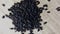 Nigella seeds or Black cumin or Black onion seed, and Black sesame seed in dish with male hand on wooden background.