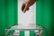 Nigeria flag, hand dropping ballot card into a box - voting, election concept