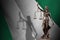 Nigeria flag with statue of lady justice and judicial scales in dark room. Concept of judgement and punishment