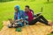 Nigerian couple working on their laptops while on a picnic on a beautiful grass-covered meadow