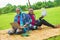 Nigerian couple working on their laptops while on a picnic on a beautiful grass-covered meadow