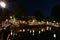 A night in Amsterdam. The illuminated bridge is reflected in the canal water. Summer. Night