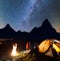 Night camping. Charming pair tourists sitting face to face in front tent near campfire under shines starry sky