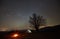 Night camping in the mountains. Hikers having a rest in tourist tent under starry sky near campfire