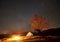 Night camping in the mountains. Hikers having a rest in tourist tent under starry sky near campfire